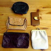 Overview of 4 leather coin purses and 1 leather key holder on wooden surface