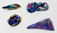Top-down photo of the four brooches arranged in a rectangular pattern showcasing their vibrant colours and varied shapes.