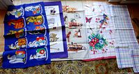 All seven linen tea towels laid out on carpet showing various designs including The Queen's Beasts, Silver Jubilee, floral, train, and checked patterns
