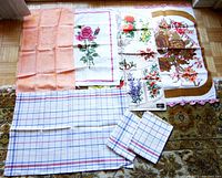 Seven linen tea towels laid out on floor showing various floral and checkered designs