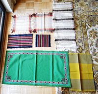 Overview of all 7 table mats and runners arranged on floor, showing sizes, colors, and fringe details.