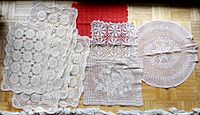 Overview photo of all nine doilies arranged on a floor, showing various sizes and rectangular and circular shapes with lace details.