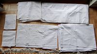 Overview of 4 folded white antique sheets and 2 folded pillowcases laid on wooden floor showing size and color variations.