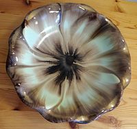 Top down photo of ceramic bowl showing flower design and wavy edges.