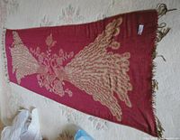 Full view of the large rectangular burgundy scarf with a large golden peacock and floral pattern, showing tassel fringe edges.