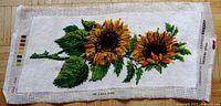 Full view of needlepoint sunflower artwork on canvas, showing two sunflowers and leaves with printed color references on edges.