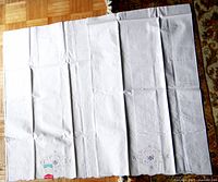 Full view of the white cotton pillowcase spread out, showing two embroidered designs at the edges.