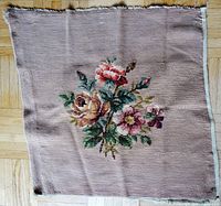 Full view of the square needlepoint fabric showing floral design centered on beige background