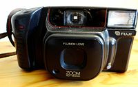 Front view of Fuji DL-800 Zoom compact camera showing Fujinon lens, zoom range markings, and built-in flash