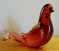 Front view of the red glass bird sculpture highlighting the smooth body and tilted head.