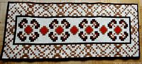 Full view of rectangular handmade needlepoint wall hanging showing entire geometric pattern and color scheme.