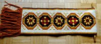 Full view of the needlepoint wall hanging showing geometric pattern with orange fringe along one edge.