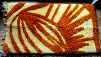 Front view of handmade rya rug showing thick shaggy wool pile with an orange and cream geometric pattern.
