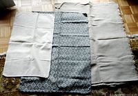 Large grey diamond patterned fabric piece with two beige heavy fabric cases placed on top.