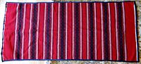 Full view of the large red table runner showing the striped and floral pattern design.