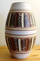 Front view of large pottery vase showing the geometric pattern and vertical ridges with earthy colors.