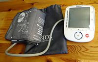 Life brand blood pressure monitor BM47 with cuff and carrying pouch on wooden surface.