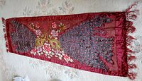 Full view of the red scarf laid flat showing the full peacock embroidery and floral design with fringed ends.