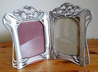 Double hinged pewter picture frame standing open showing front and inner sides with floral motifs