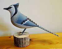 Side view of handmade pottery Blue Jay bird on wooden base, showing detailed paintwork and bird profile.