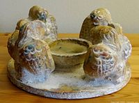 Top and side views of the pottery candle holder showcasing four kneeling angels around a circular base and central candle holder.