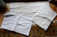 Rectangular white linen or linen-like fabric runner or tablecloth, folded showing texture and size