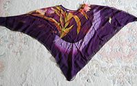 Sheer purple scarf or cape with floral design laid flat showing overall colors and pattern.
