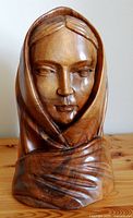 Front view of hand-carved solid wood sculpture of a woman's face with detailed shawl.