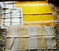 Photo showing the woven runner, the two embroidered runners, and the yellow tablecloth with white Greek key design.