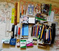 Photo showing wide variety of used office supplies including rulers, pens, staplers, ink, paper clips, and note pads.