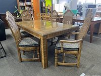 Full view of the wood dining table set with six chairs around it in a showroom setting.
