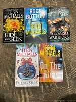 Top-down view of all five paperback books arranged on carpet, showing cover art and titles.