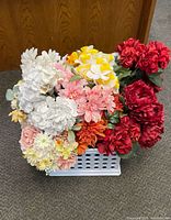 Front view of a large basket filled with multicolor artificial flowers including red, white, pink, yellow, and orange silk flower varieties arranged compactly.