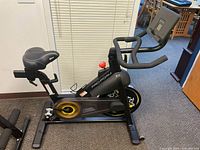 Side view image showing the full ProForm CBC exercise bike with black frame, yellow flywheel accents, and comfort saddle.