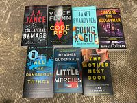 Top down view of seven paperback books with front covers showing titles and author names.