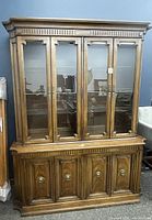 Front view of the Thomasville hutch showing four glass doors and paneled wooden cabinet below.