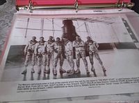 Black-and-white promotional photo showing The Right Stuff movie astronauts in flight suits posed in front of space capsule.