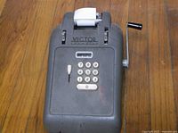 Full top view of the antique Victor Champion adding machine showing keypad, crank handle, and paper roll.