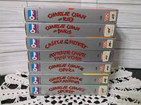 Stack of 7 Charlie Chan movie VHS tapes viewed from the spine showing titles: Charlie Chan in Rio, Charlie Chan in Paris, Charlie Chan in the Desert, Murder Over New York, Charlie Chan in Odessa, Charlie Chan's Secret, and one more with label unclear.