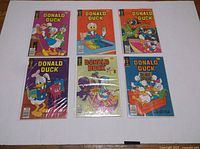 Six Donald Duck comics laid out on a white surface, each in a protective bag and board.
