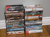Photo of two stacks of DVD movies showing a variety of titles and artwork on the spines, includes some clearly readable movie titles.