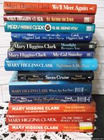 Stack of 13 Mary Higgins Clark hardcover books with dust jackets visible, titles legible, showing spine details.