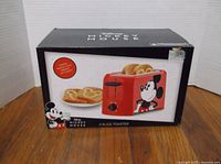 Boxed Disney Mickey Mouse 2-slice toaster with side graphic showing Mickey and images of toasted bread with Mickey icon imprint