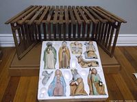 Wooden creche with ceramic nativity figures set on table, figures placed in foam packaging insert