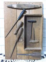 Full view of vintage wooden wall hanging with six old hand tools mounted on it.