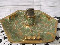 Close-up of vintage ashtray and lighter showing green leaf design with gold accents