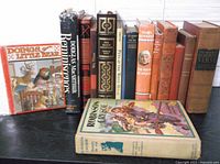 Books on a shelf showing front spines and some full covers including Robinson Crusoe and The Doing of Little Bear.