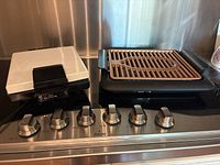 Electric grill and sandwich maker with brown non-stick ceramic and titanium coated grill plates and black handles showing Gotham Steel branding.