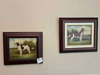 Two oil paintings depicting dogs, framed and hung on a wall.