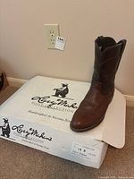 Single brown men's cowboy boot on box with Larry Mahan Bullhide Collection branding, showing style and size label.